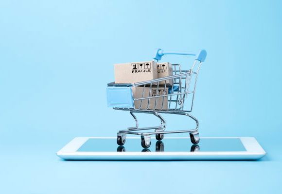 Isolated of Shipping paper boxes inside blue shopping cart trolley on tablet with blue background and copy space , Online shopping and e-commerce concept.